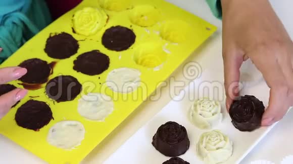 一个女人从硅胶模具中取出用黑白巧克力釉的现成糖果视频的预览图