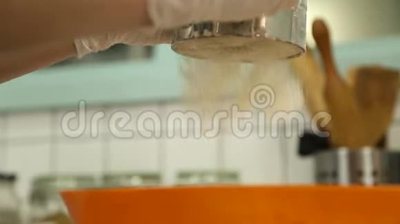 厨房里的女人用筛子把面粉倒入黄色的盘子里视频的预览图