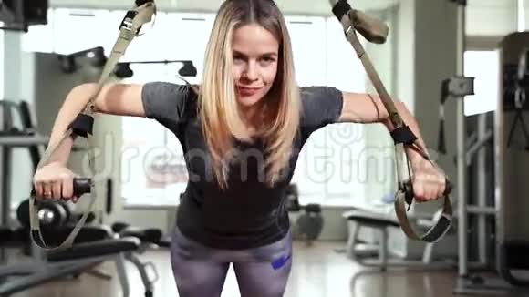 年轻有魅力的女人做核心腹肌交叉训练与健身带在健身房TRX视频的预览图