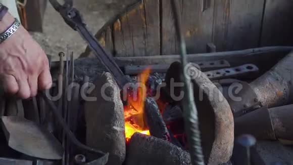 铁匠和铁匠一起工作的铁匠在锻造热金属部分着火了然后踩了视频的预览图