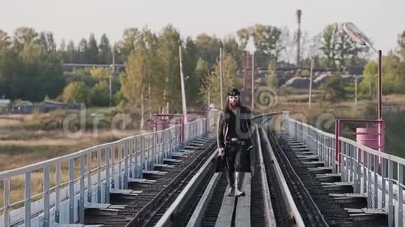 一个真正的硬汉走过桥走向相机侧视日落视频的预览图