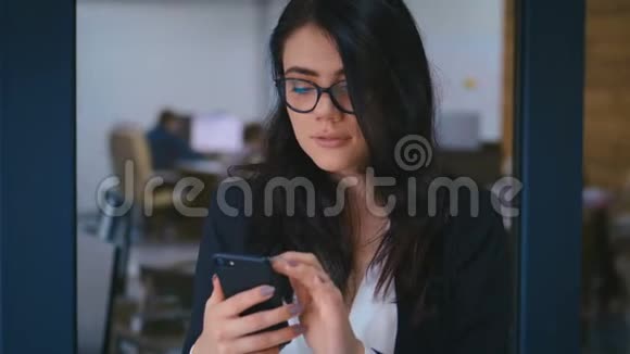 办公室使用智能手机的美丽年轻女性肖像商务女士正式着装时的打字信息视频的预览图