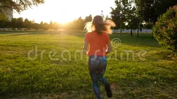 运动妇女在城市公园日落时在草地上慢跑慢动作视频的预览图