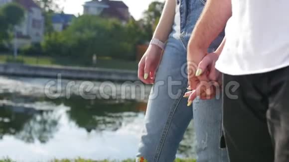 亲密的两个情人携手男人和女人牵着手站在池塘附近的细节轮廓视频的预览图