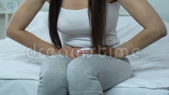 女性坐在床上抱着胃月经痉挛腹痛疾病视频的预览图
