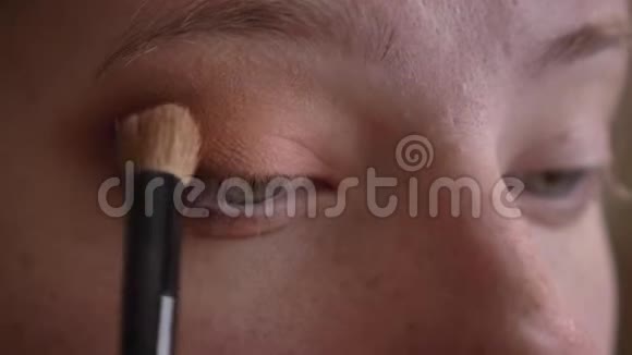 年轻的白种人女化妆师用深色的棕色眼影拍摄光滑的眼睛视频的预览图