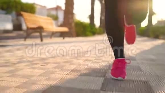 日落时一个女人沿着棕榈大道奔跑的腿慢动作视频的预览图