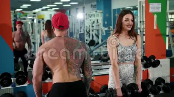 男人和女人同时弯曲手臂通过举起哑铃在健身房锻炼视频的预览图