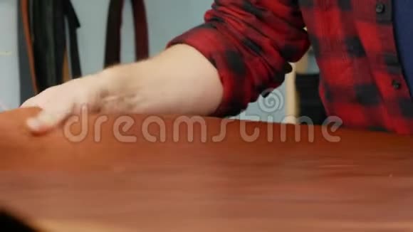 皮革工人摸着桌子上的一大块皮革男性皮革工匠检查皮肤缺陷视频的预览图