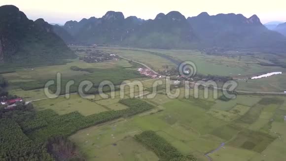 在绿色的田野和平静的小村庄上空飞行视频的预览图