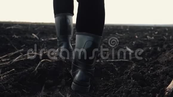 日落时分一个农民穿着橡胶靴在阳光下的一片犁地上散步农业耕作视频的预览图