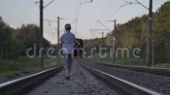 带旅行包的有趣男孩坐火车去户外视频的预览图