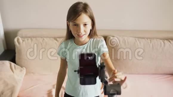 一个年轻女孩通过在三脚架上安装智能手机进行在线广播视频的预览图