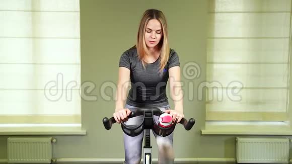 把年轻女人的饮用水装在健身房里肌肉发达的妇女在运动后休息视频的预览图