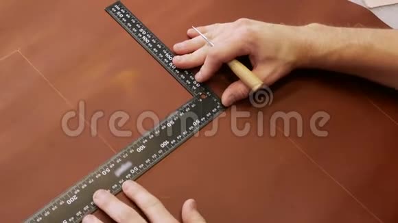 俯视图年轻的工匠用尺子在皮布上做一行标记手工皮革制品视频的预览图