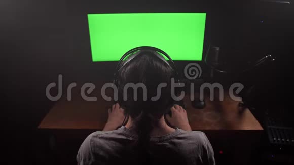 一个戴着耳机的人看着显示器的绿色屏幕摘下耳机看着屏幕开始打字视频的预览图