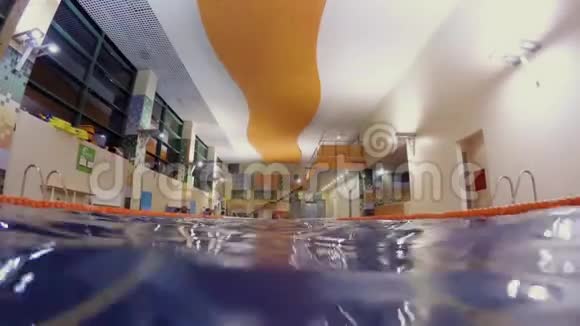 在空荡荡的游泳池里一个戴着红帽子的人向镜头爬去视频的预览图
