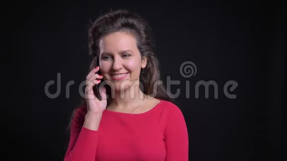 白种人女人在黑色背景下愉快地使用智能手机交谈的肖像视频的预览图