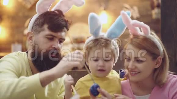 幸福的家庭正在为复活节做准备可爱的小男孩戴着兔子耳朵复活节快乐的概念有胡子的男人视频的预览图
