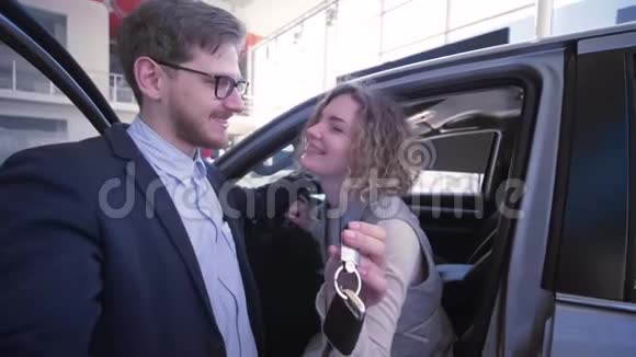 在汽车沙龙新购汽车附近带钥匙的微笑家庭在智能手机上拍照手机视频的预览图