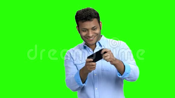 快乐的亚裔男子在他的手机上玩游戏视频的预览图