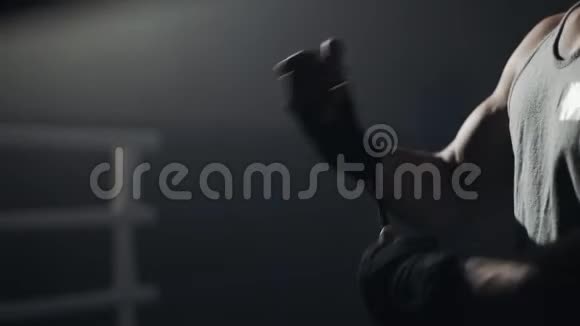 年轻人用黑色拳击把手裹在黑暗的戒指里剪影慢动作拳击概念视频的预览图