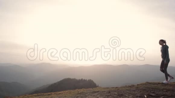 在日落的背景下两个徒步旅行者站在山脊边缘举起双手的剪影受污染的视频的预览图