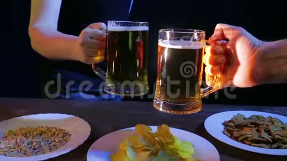 酒吧里的朋友的手在黑色的背景上碰到啤酒杯视频的预览图