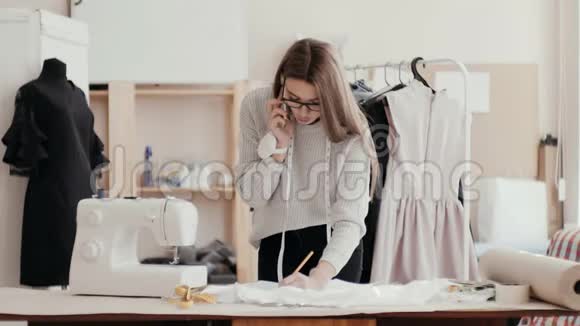 商务女设计师在电话中交谈同时在织物上打上标记那个女孩穿着黑色的衣服视频的预览图