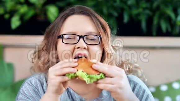 一位身材肥胖的微笑女人在镜头前享受着美味可口的美味汉堡视频的预览图