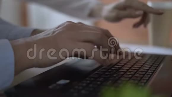 特写镜头男人手主动快速地打字在笔记本电脑的键盘上背景中的女性有助于指出视频的预览图