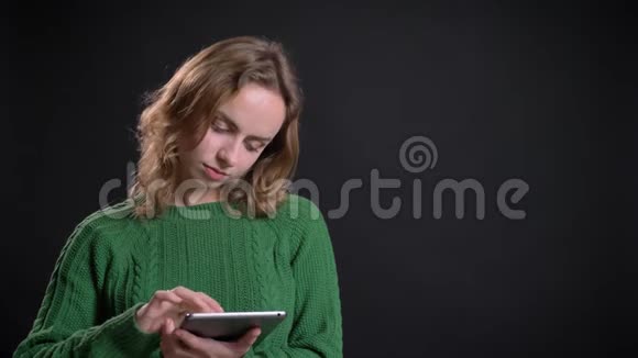 在平板电脑上滚动的白种人成年女性的特写肖像看着镜头微笑视频的预览图