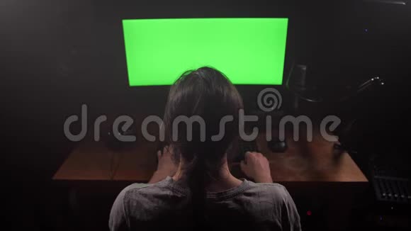 绿色屏幕一个男人看着显示器然后戴上耳机4K慢慢视频的预览图