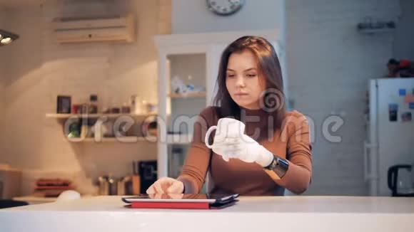 一位女士用杯子里的仿生手饮料操作平板电脑视频的预览图