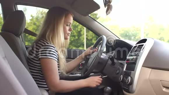 一个年轻的女人坐在汽车的车轮后面打开点火钥匙视频的预览图