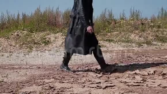 一个穿着黑色雨衣和帽子的硬汉穿过沙漠他看起来像个追踪者视频的预览图