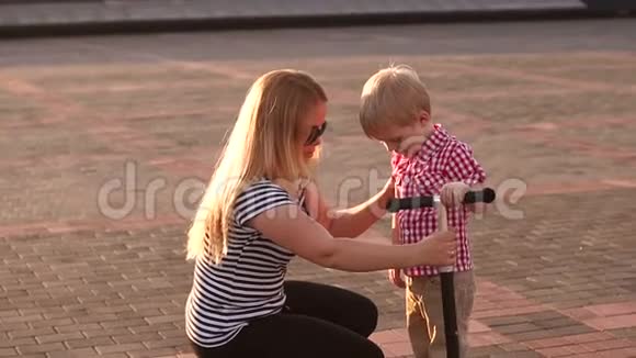 日落时分一位母亲和儿子在城市公园散步的特写镜头视频的预览图