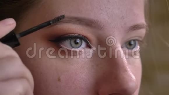 年轻的白种人女化妆师用黑色睫毛膏来修饰她的眉毛视频的预览图