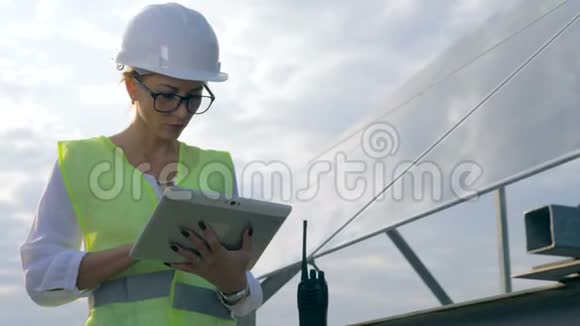 女工程师在太阳能电池板附近的平板电脑上工作关闭视频的预览图
