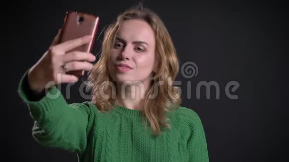 一位白种人成年女性的特写照片她在电话中打了一个视频电话微笑着用手挥手问好视频的预览图
