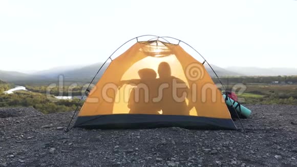 从山上拥抱的影子男人和女人的帐篷里看视频的预览图