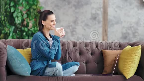 迷人的家庭年轻女性在客厅舒适的沙发上喝咖啡享受休息视频的预览图