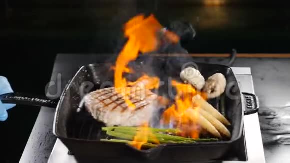 专业厨师在餐厅厨房烹制火焰式菜肴火锅点火搅拌视频的预览图