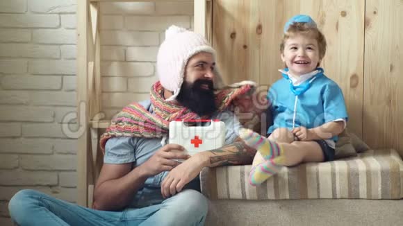 穿着医生衣服的小男孩和他父亲玩年轻的医生父子在家打诊所视频的预览图