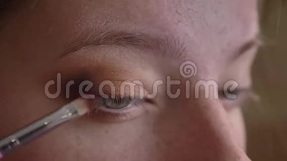 年轻的白种人女化妆师将深棕色眼影贴在她的上睑上视频的预览图