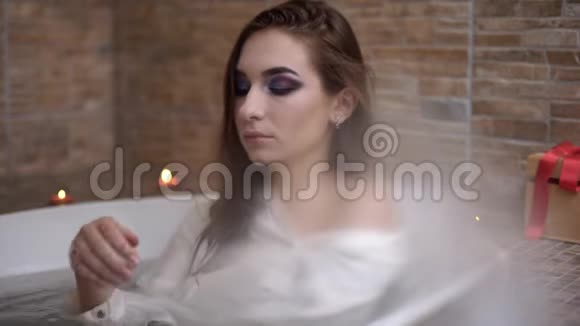 穿白衬衫洗澡的美女画像可爱的女孩在浴室里享受着燃烧的蜡烛视频的预览图
