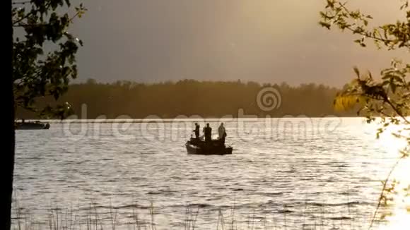 日落时分渔民在湖边的摩托船上捕鱼的剪影视频的预览图