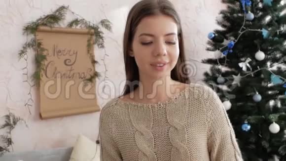 女孩坐在圣诞树旁边的床上新年气氛视频的预览图