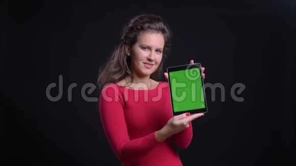 红衣白种女人的画像在黑色背景下欢快地将平板电脑的绿色屏幕映入镜头视频的预览图