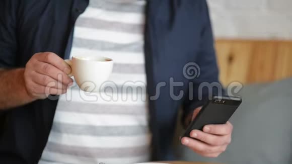 商人特写他早餐时工作拿着他的智能手机喝着咖啡或茶视频的预览图